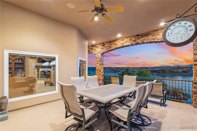 view of patio with a water view, ceiling fan, and outdoor dining area