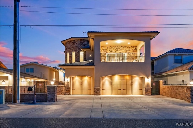 view of front of house featuring a balcony, an attached garage, fence, and stucco siding