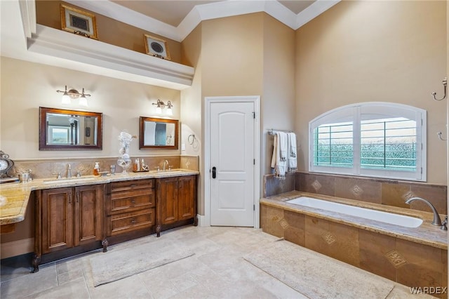 bathroom with a sink, double vanity, a bath, and a towering ceiling