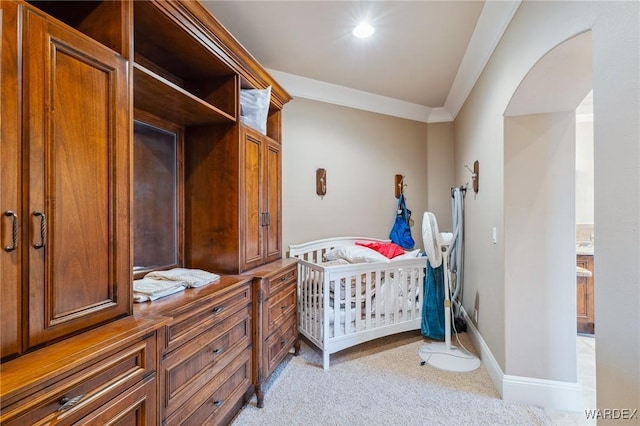 bedroom featuring baseboards, arched walkways, crown molding, and light colored carpet