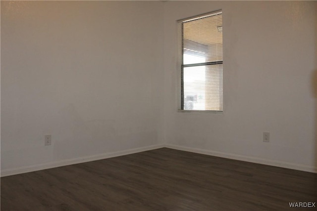 unfurnished room with dark wood-style flooring and baseboards