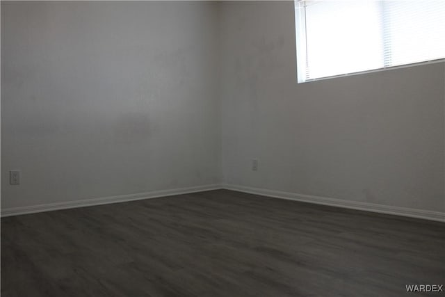 spare room with dark wood-style floors and baseboards