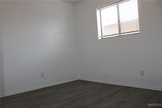 spare room with dark wood-style floors and baseboards