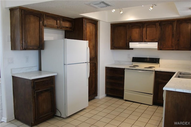 kitchen with dark brown cabinetry, under cabinet range hood, white appliances, visible vents, and light countertops