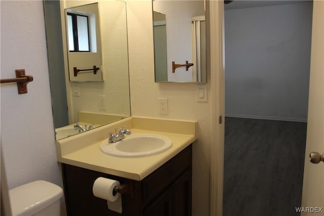 bathroom with wood finished floors, vanity, and toilet