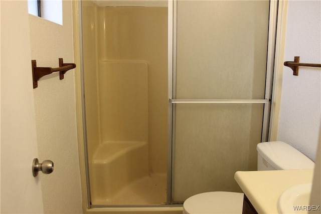 bathroom with toilet, a stall shower, and vanity