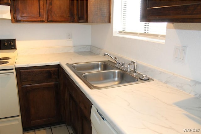 kitchen with light stone counters, white appliances, a sink, and dark brown cabinetry