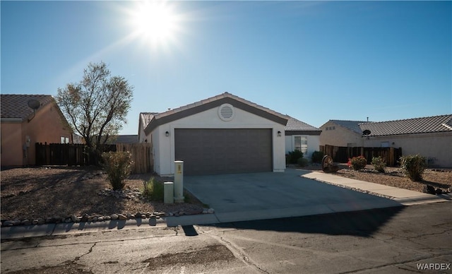 ranch-style home featuring a garage, fence, concrete driveway, and stucco siding