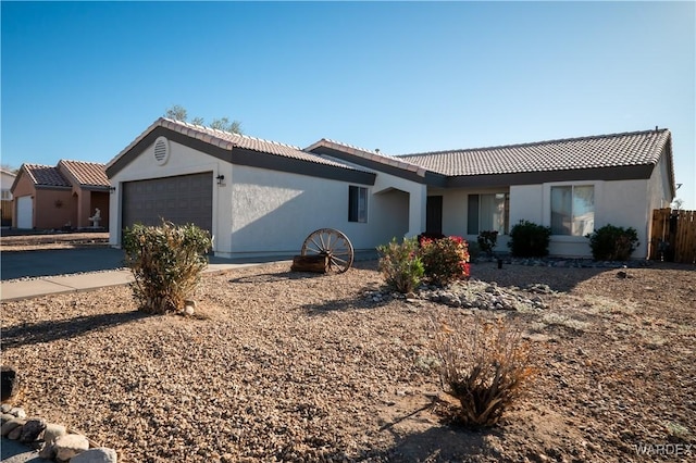 ranch-style house featuring a tiled roof, an attached garage, and stucco siding