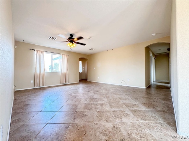 spare room featuring ceiling fan, visible vents, arched walkways, and baseboards