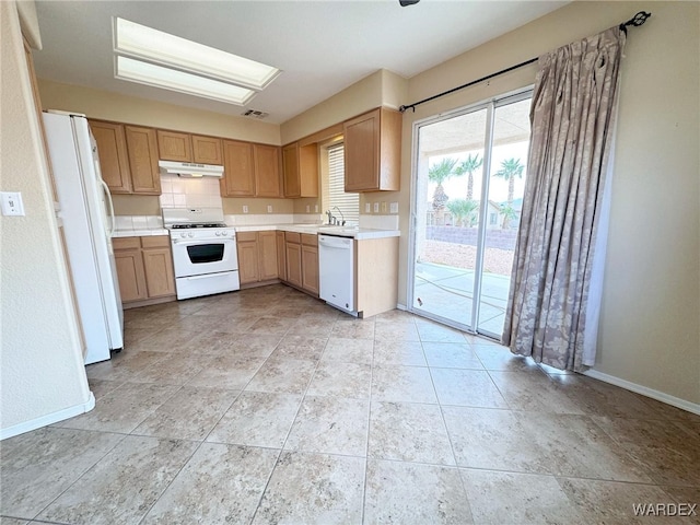 kitchen with white appliances, under cabinet range hood, baseboards, and light countertops