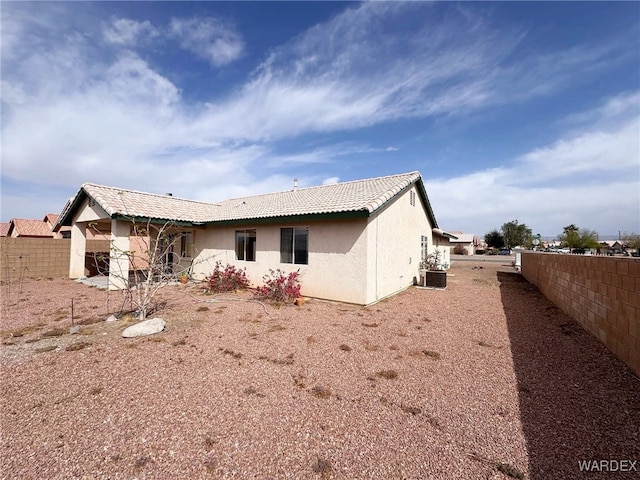 back of house with central AC unit, a tile roof, fence, and stucco siding