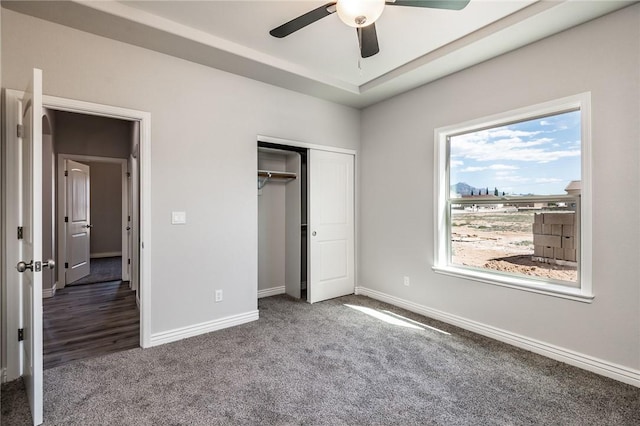 unfurnished bedroom with carpet, a closet, baseboards, and ceiling fan