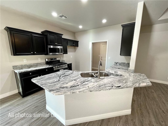 3371 N Apache St, Kingman, AZ 86401 - kitchen featuring stainless steel appliances, a sink, dark cabinetry, light wood-style floors, and a peninsula