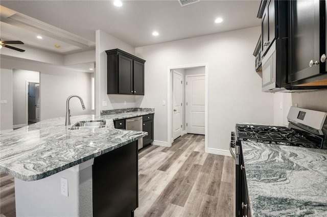kitchen featuring appliances with stainless steel finishes, a sink, light wood-style flooring, light stone countertops, and recessed lighting