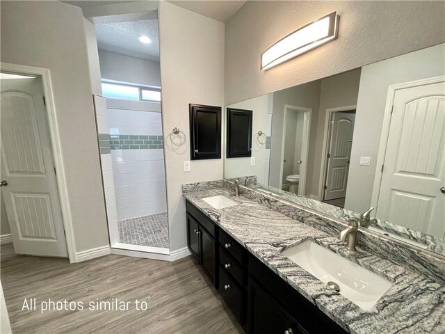 3371 N Apache St, Kingman, AZ 86401 - bathroom featuring wood finished floors, a walk in shower, baseboards, toilet, and double vanity