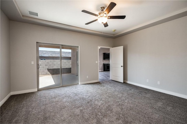 carpeted spare room with ceiling fan, baseboards, and a tray ceiling