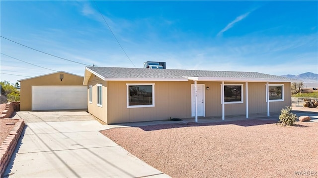 single story home with a detached garage and roof with shingles