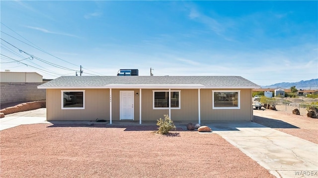 ranch-style house with central AC unit, roof with shingles, and fence