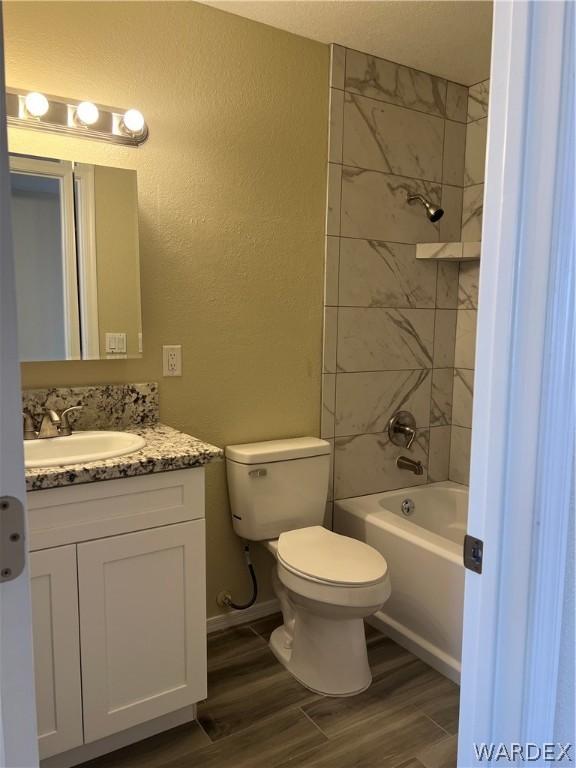 full bathroom featuring shower / bath combination, a textured wall, toilet, vanity, and wood finished floors