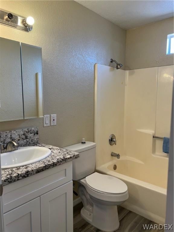 bathroom featuring bathtub / shower combination, a textured wall, toilet, vanity, and wood finished floors