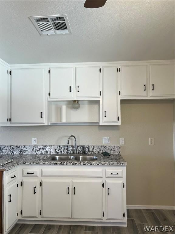 kitchen with white cabinetry, visible vents, and a sink