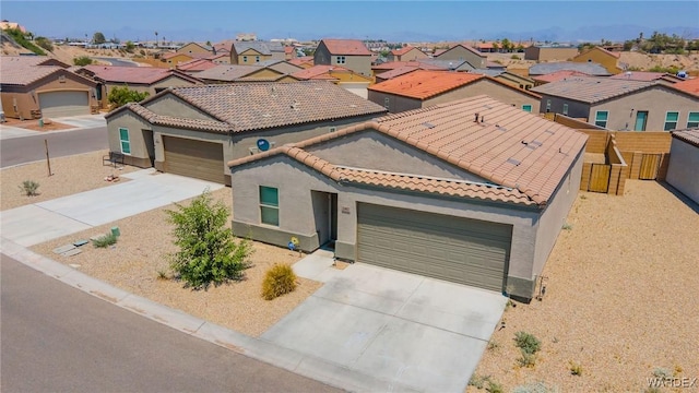 mediterranean / spanish house featuring a tiled roof, an attached garage, fence, and driveway