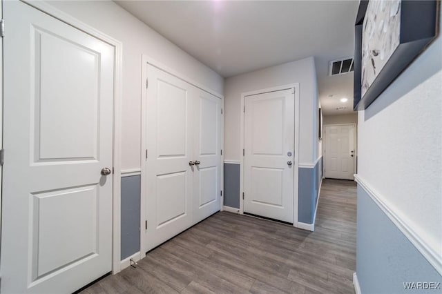 hallway with light wood-style floors, baseboards, and visible vents