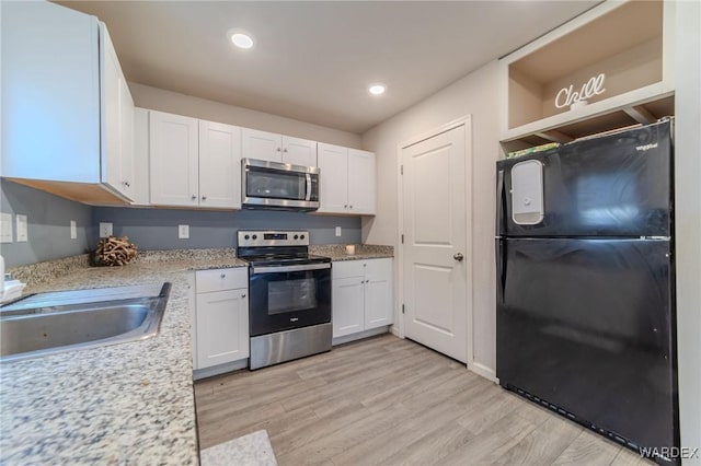 kitchen with a sink, white cabinetry, appliances with stainless steel finishes, light wood-type flooring, and open shelves