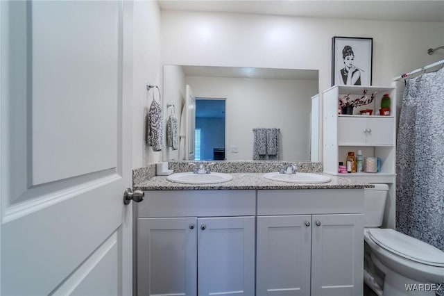 bathroom featuring double vanity, toilet, and a sink