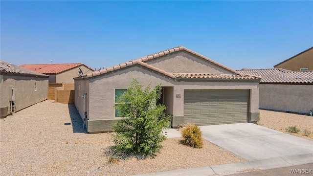 mediterranean / spanish-style house with concrete driveway, a tiled roof, an attached garage, fence, and stucco siding