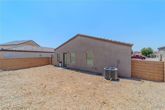 rear view of property featuring central air condition unit, a fenced backyard, and stucco siding