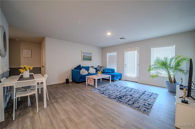 living room with baseboards, visible vents, and light wood-style floors