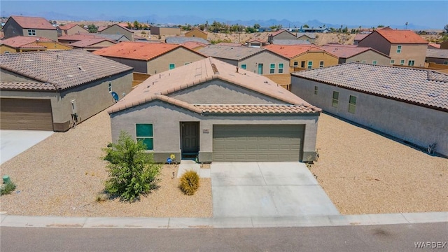 mediterranean / spanish house with a garage, a residential view, concrete driveway, and a tile roof