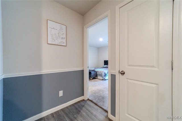 corridor featuring baseboards and wood finished floors