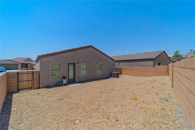 back of property with central AC, a fenced backyard, and stucco siding