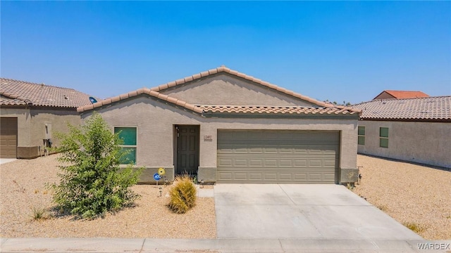 view of front of house with concrete driveway, a tiled roof, an attached garage, and stucco siding