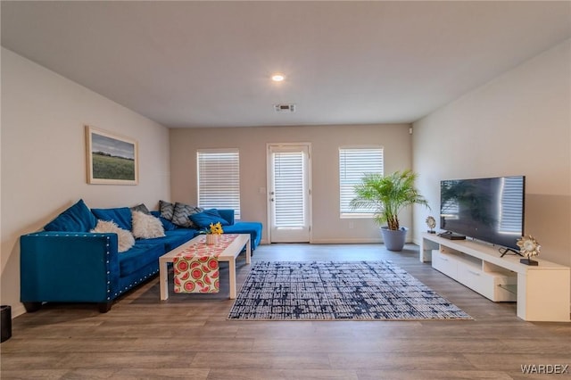 living area featuring wood finished floors, visible vents, and baseboards