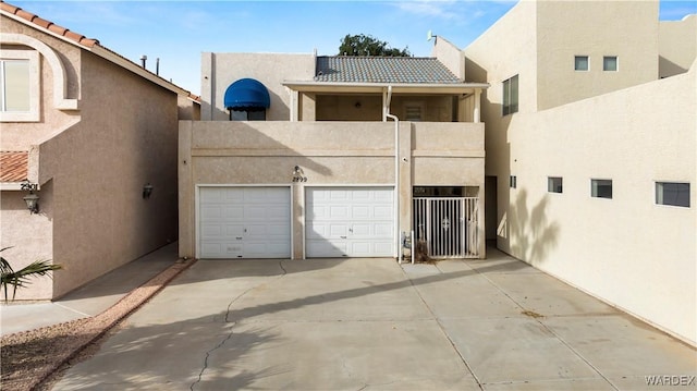 view of front of home with driveway, a garage, a balcony, a tile roof, and stucco siding