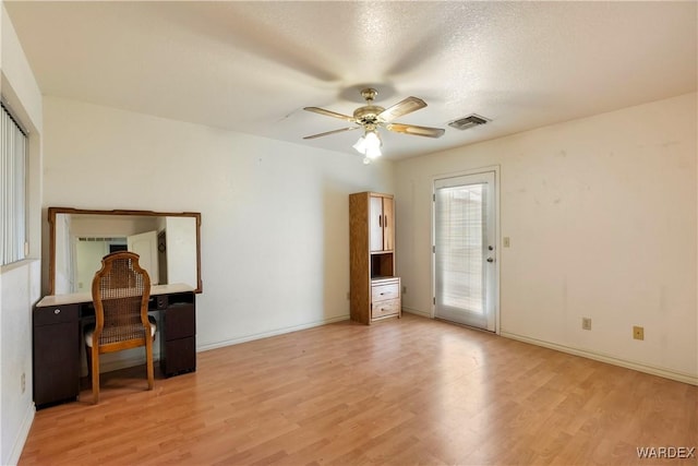 interior space featuring visible vents, ceiling fan, a textured ceiling, light wood-type flooring, and baseboards