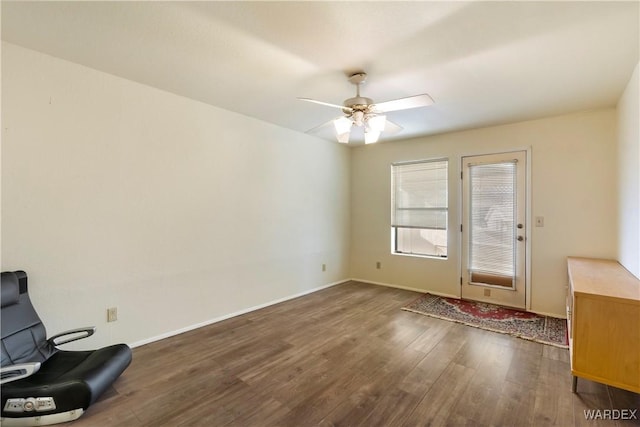 interior space with a ceiling fan, baseboards, and dark wood-type flooring