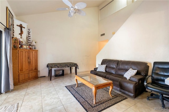 living room featuring visible vents, light tile patterned flooring, ceiling fan, and a towering ceiling