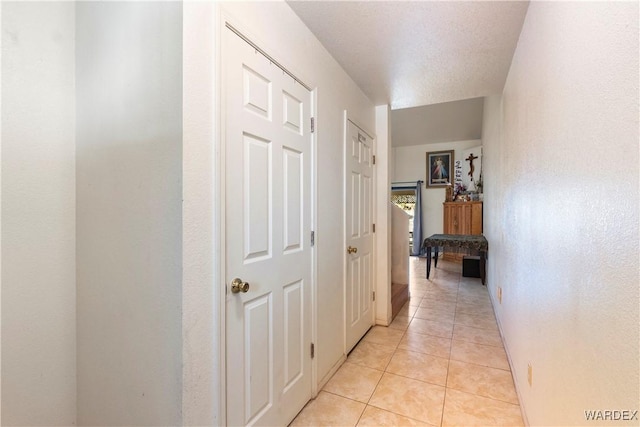 corridor with a textured ceiling and light tile patterned floors