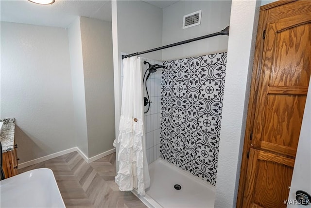 full bath featuring a stall shower, visible vents, and baseboards