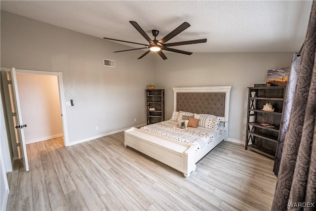 bedroom featuring a textured ceiling, visible vents, vaulted ceiling, and wood finished floors