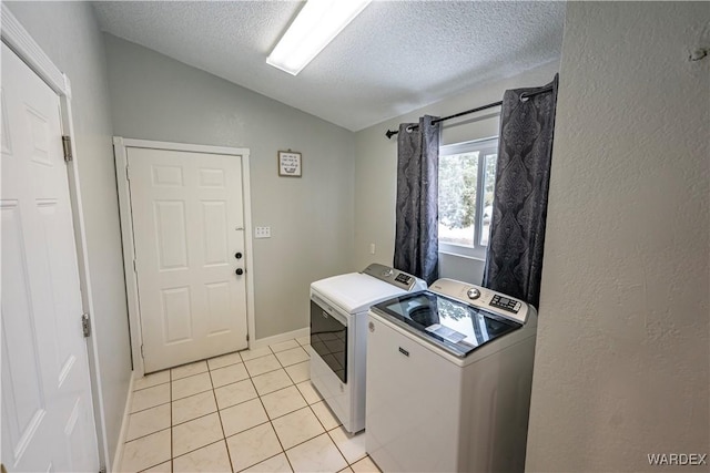 washroom featuring a textured wall, light tile patterned flooring, a textured ceiling, laundry area, and independent washer and dryer