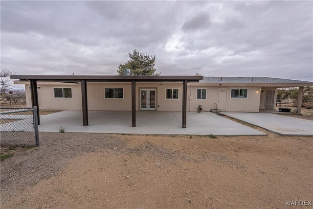 rear view of property featuring stucco siding, fence, a patio, and french doors