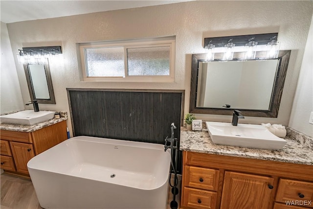 bathroom with a textured wall, a freestanding tub, and a sink