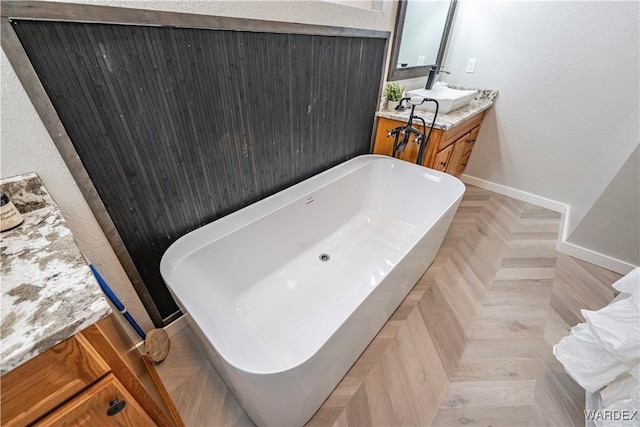 bathroom featuring a soaking tub, vanity, and baseboards