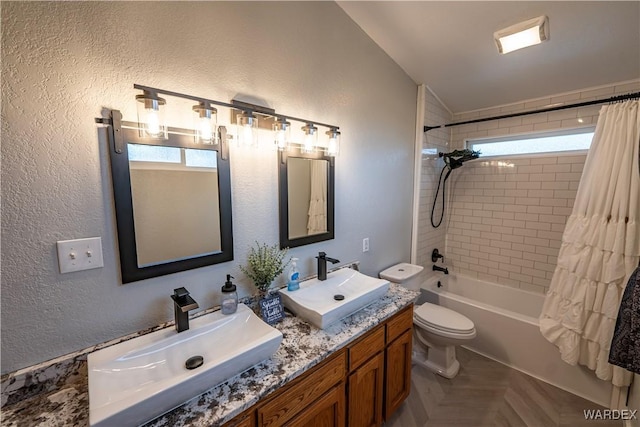 bathroom featuring a sink, shower / bathtub combination with curtain, toilet, and double vanity